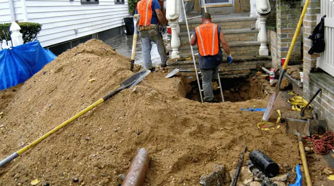 Contractors performing foundation protection and exterior drainage excavation near residential home steps in Jersey City, NJ